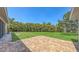 Large backyard featuring a brick patio and lush greenery, ideal for outdoor activities and entertaining at 5698 Country Walk Ln, Sarasota, FL 34233
