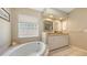 Bright bathroom featuring a soaking tub, tile flooring, and double vanity with neutral countertops at 5698 Country Walk Ln, Sarasota, FL 34233