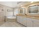 Bathroom with double vanities, soaking tub, and neutral tile at 5698 Country Walk Ln, Sarasota, FL 34233