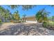 Home showcasing a paved driveway and lush tropical landscaping, with a neutral color scheme at 5698 Country Walk Ln, Sarasota, FL 34233