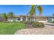 Beautiful home with a well-manicured lawn, colorful flowers, and a brick driveway at 5698 Country Walk Ln, Sarasota, FL 34233