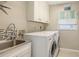 Laundry room with stainless steel sink, washer and dryer, and storage cabinets at 5698 Country Walk Ln, Sarasota, FL 34233