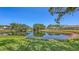 Scenic view of a pond surrounded by green grass and mature trees, creating a tranquil environment at 5698 Country Walk Ln, Sarasota, FL 34233
