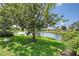 Backyard lake view with trees, shrubs, and grass at 5787 Ivrea Dr, Sarasota, FL 34238