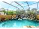 Screened in pool with rock waterfall feature surrounded by lush landscaping at 5905 32Nd E St, Ellenton, FL 34222
