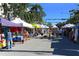 Lively outdoor market scene with vendors and shoppers enjoying a sunny day, offering various goods and community engagement at 631 N Orange Ave # 208, Sarasota, FL 34236