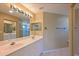 Well-lit bathroom featuring a double vanity, a large mirror, and a tiled floor and is accessible through a sliding door at 6335 Bay Cedar Ln, Bradenton, FL 34203