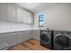Well-lit laundry room with modern washer and dryer, gray cabinets, white countertop, and wood flooring at 6349 Isla Del Ray Ave, Sarasota, FL 34240