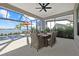 Covered lanai featuring outdoor dining table, ceiling fan, and waterfront views with screened enclosure at 6349 Isla Del Ray Ave, Sarasota, FL 34240
