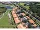 Aerial view of residential community near a golf course and pond, highlighting red tiled roofs and lush trees at 7155 Boca Grove Place Pl # 202, Lakewood Ranch, FL 34202