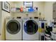 Functional laundry room with modern washer and dryer units, plus storage shelving at 7155 Boca Grove Place Pl # 202, Lakewood Ranch, FL 34202