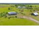 Scenic view of a gray home on a vast green property with multiple outbuildings at 7745 Wauchula Rd, Myakka City, FL 34251
