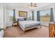 Bright bedroom featuring neutral carpet, blue accents, and large windows offering a view of the outdoors at 7745 Wauchula Rd, Myakka City, FL 34251