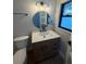 Bathroom with wood vanity with white countertop, round mirror and contemporary lighting at 808 25Th W Ave, Palmetto, FL 34221