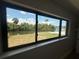 Waterfront view through a large picture window showcasing lush greenery and a private dock at 808 25Th W Ave, Palmetto, FL 34221