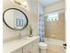 Bathroom features oval mirror, white vanity, and tiled shower-tub at 8206 Heritage Grand Pl, Bradenton, FL 34212