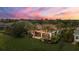 Expansive home exterior showcasing a central pool, covered patio, palm trees, and lush green lawn under a colorful evening sky at 8312 Catamaran Cir, Lakewood Ranch, FL 34202