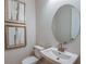 Well lit bathroom featuring a pedestal sink, toilet and a decorative mirror and artwork at 8583 Big Dipper Dr, Sarasota, FL 34241