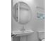 Bright bathroom features a pedestal sink, round mirror, and natural light from the window at 8632 Snowfall St, Sarasota, FL 34241