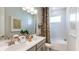 Well-lit bathroom with a double vanity, framed mirror, and a shower-tub combination with leaf-patterned curtain at 8632 Snowfall St, Sarasota, FL 34241