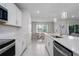 Bright kitchen featuring white cabinets, stainless appliances, a quartz island, and an adjacent dining area at 9148 Royal River Cir, Parrish, FL 34219