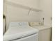 Well-lit laundry space includes a washer, dryer, and overhead shelf for storage solutions at 933 Sunridge Way # B5, Sarasota, FL 34234
