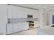 Bright kitchen features white cabinets, stainless steel appliances, marble countertops, and tiled backsplash at 9719 Discovery Ter, Bradenton, FL 34212