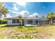 Home exterior with a screened-in pool and generous lawn space, framed by mature trees at 10055 Franklin Dr, Englewood, FL 34224