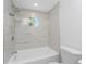Beautiful white bathroom featuring marble-look tiling and a view from a uniquely-shaped window at 10055 Franklin Dr, Englewood, FL 34224
