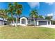 Charming single-story home featuring a manicured lawn and palm trees against a clear blue sky at 10055 Franklin Dr, Englewood, FL 34224