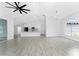 Open living room with kitchen, gray flooring, modern ceiling fan, and natural light at 10055 Franklin Dr, Englewood, FL 34224