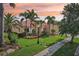 Lovely single-story home with lush landscaping, palm trees, and a terracotta roof at sunset at 1251 Tuscany Blvd, Venice, FL 34292