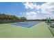 Well-maintained tennis court surrounded by fencing, trees and an array of green foliage at 1251 Tuscany Blvd, Venice, FL 34292