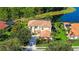 Aerial view of a yellow stucco house, terra cotta tile roof, solar panels, mature trees, and pond at 12520 Natureview Cir, Bradenton, FL 34212