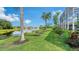 A sprawling backyard features a grassy lawn, tropical trees and shrubs, and the serene lake that adds natural beauty at 12520 Natureview Cir, Bradenton, FL 34212