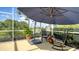 A relaxing screened-in lanai is furnished with outdoor seating and an umbrella to provide shade while enjoying the calming lake view at 12520 Natureview Cir, Bradenton, FL 34212