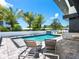 Luxurious pool area with palm trees, lounge chairs, and an outdoor kitchen, perfect for relaxation and entertainment at 1323 Loma Linda Ct, Sarasota, FL 34239