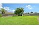 Spacious backyard with lush green lawn, mature tree, and wood fence at 1334 De Prie Rd, Englewood, FL 34223