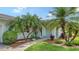 Inviting front entrance with tropical landscaping, mature palm trees and a covered front porch at 1334 De Prie Rd, Englewood, FL 34223