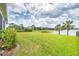 A lush green backyard leads to a serene lake view, with palm trees adding a tropical touch to this home at 13549 Old Creek Ct, Parrish, FL 34219