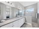 Bright bathroom features double sinks, large mirror, tiled walk-in shower and modern fixtures at 13549 Old Creek Ct, Parrish, FL 34219