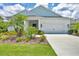 Charming single-story home features a two-car garage and meticulously landscaped front yard with palm trees at 13549 Old Creek Ct, Parrish, FL 34219