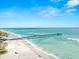 Aerial view of a pier extending into turquoise waters, with a sandy beach and scattered people along the shore at 138 Tiziano Way, North Venice, FL 34275