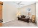 Neutral bedroom features a brown loveseat, wooden chair, and ceiling fan for a relaxing atmosphere at 138 Tiziano Way, North Venice, FL 34275