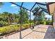 Spacious screened-in patio with brick flooring offers picturesque views of the surrounding greenery at 138 Tiziano Way, North Venice, FL 34275
