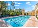 Resort-style swimming pool with lap lanes, blue lounge chairs, and lush landscaping under a sunny sky at 138 Tiziano Way, North Venice, FL 34275