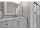 A bathroom features a single sink vanity with a white countertop, decorative mirror, and a glass door shower at 1409 57Th W St # 1409, Bradenton, FL 34209