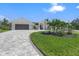 Beautiful single-story home with a well-manicured lawn and inviting, tiled driveway and arched entryway at 1527 Buoy Ln, Osprey, FL 34229