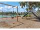 Community playground featuring swings and a slide near a fenced-in tennis court and picnic tables at 1527 Buoy Ln, Osprey, FL 34229