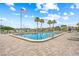 Community pool area with lounge chairs, American flag, and palm trees under a clear blue sky at 1527 Buoy Ln, Osprey, FL 34229